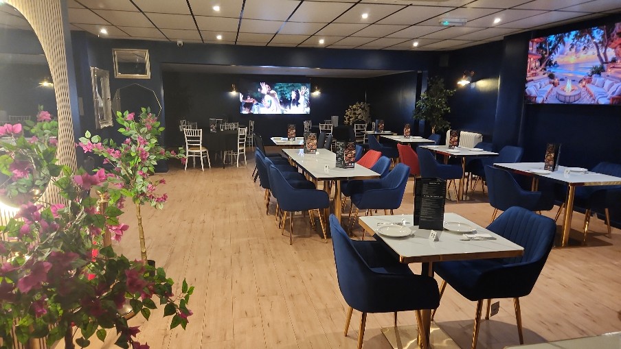 Mystique dining room with navy velvet chairs, marble tables and wall-mounted TVs